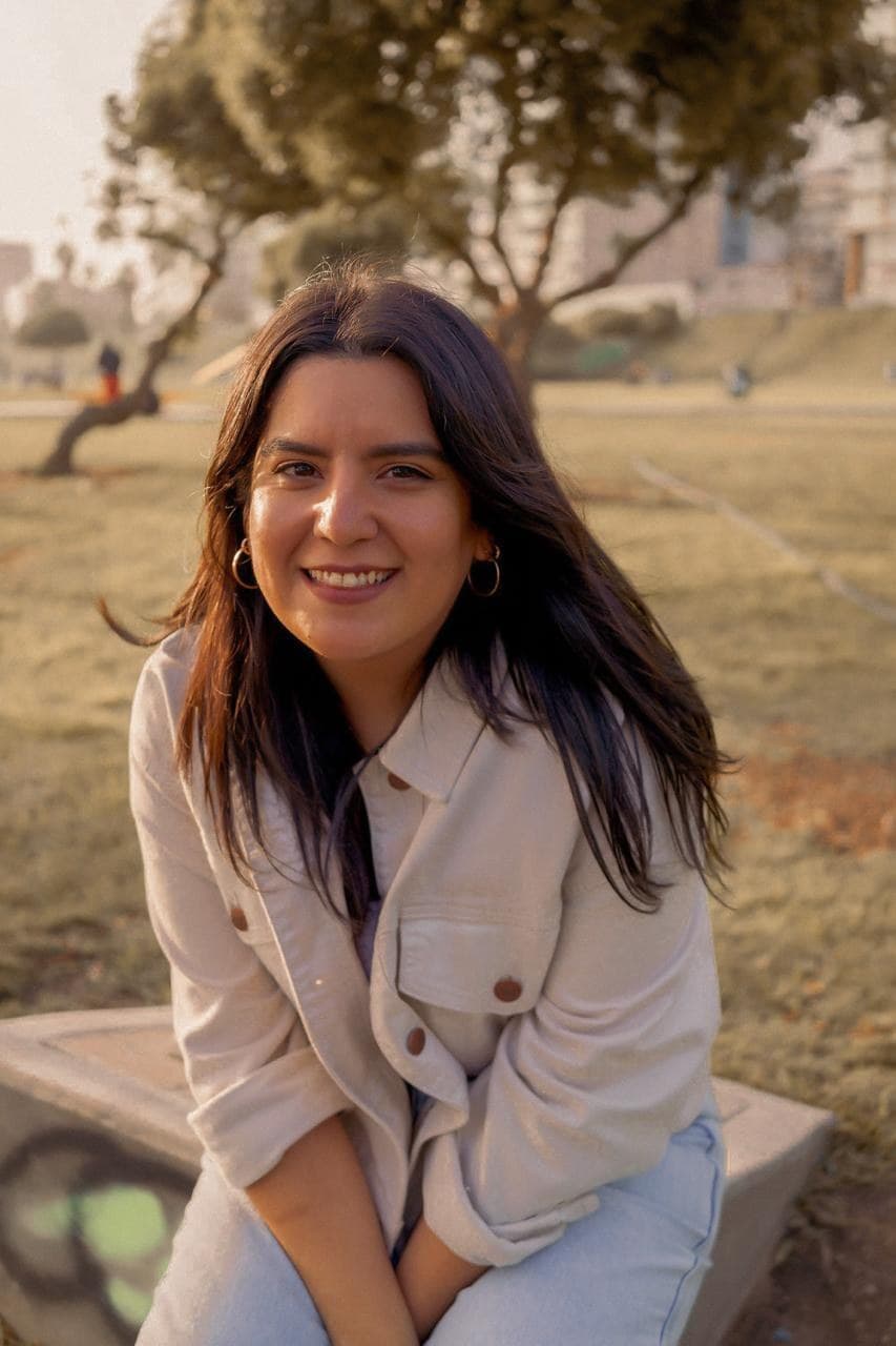 Jessika smiling, sitting in a park at golden hour